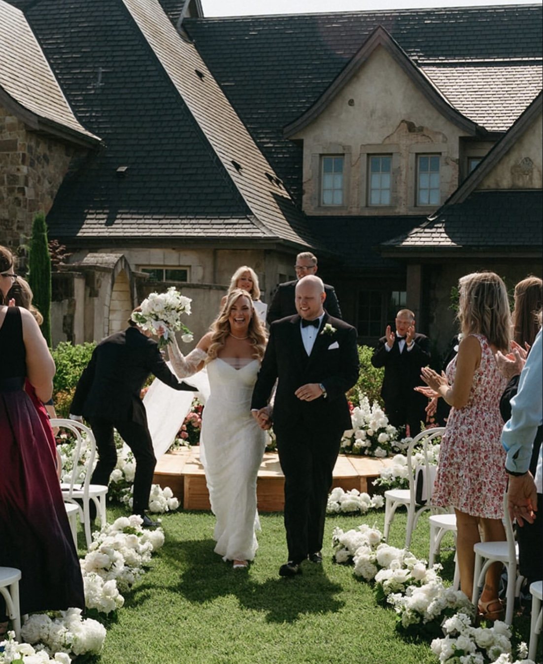 Newlywed couple walking away from their ceremony as guests celebrate