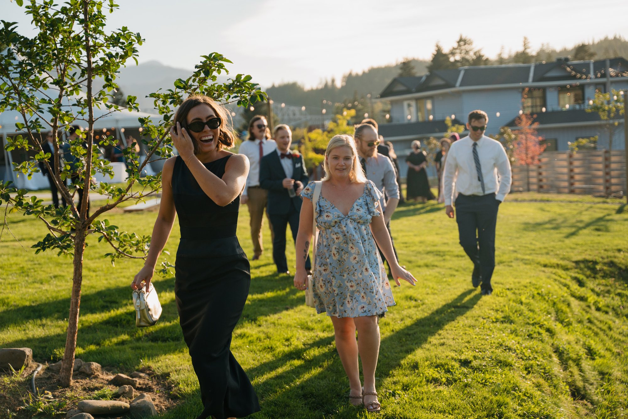 Wedding party walking together across a sunlit lawn